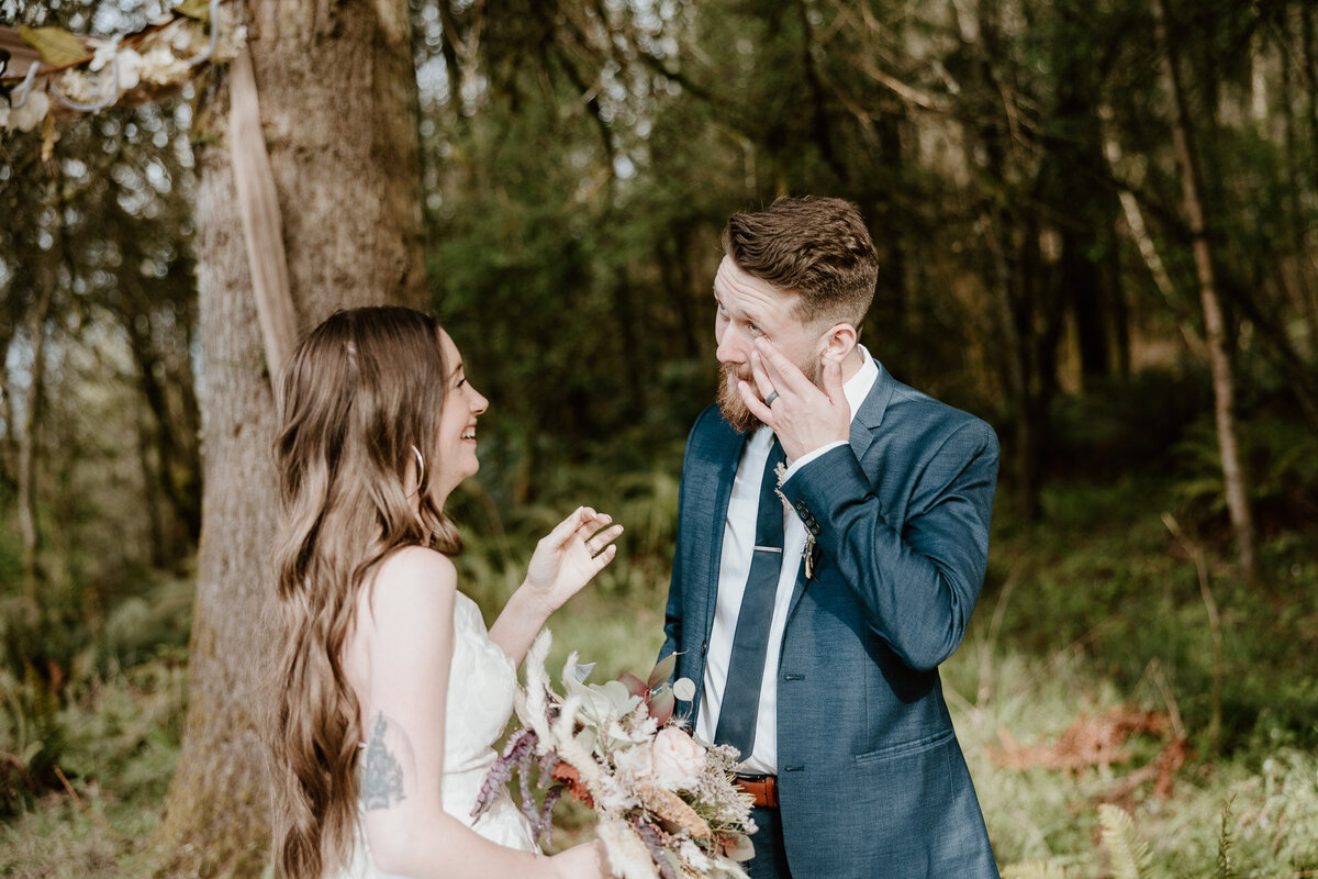 bride and groom exchanging rings during their forest oregon wedding