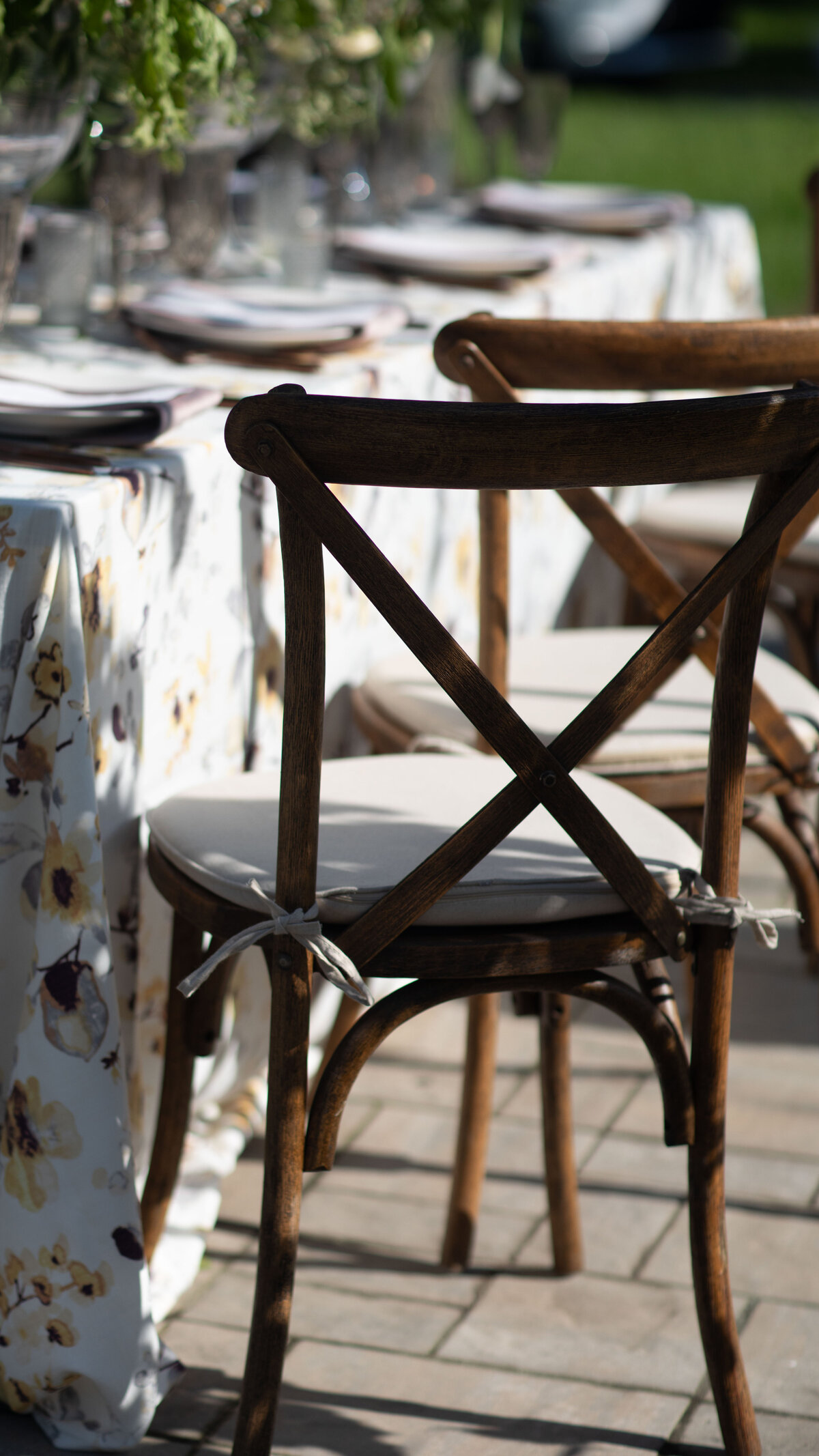 crossback chairs with linen pads at a table covered with  a linen tablecloth of neutral leaves and flowers on the patio at Willowbrook Wedding venue