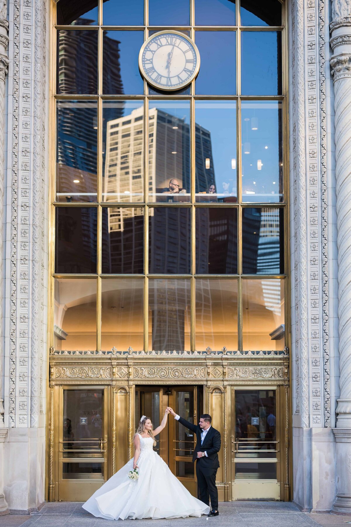 Bride twirling in front of glass doors at the wrigley building in downtown Chicago.