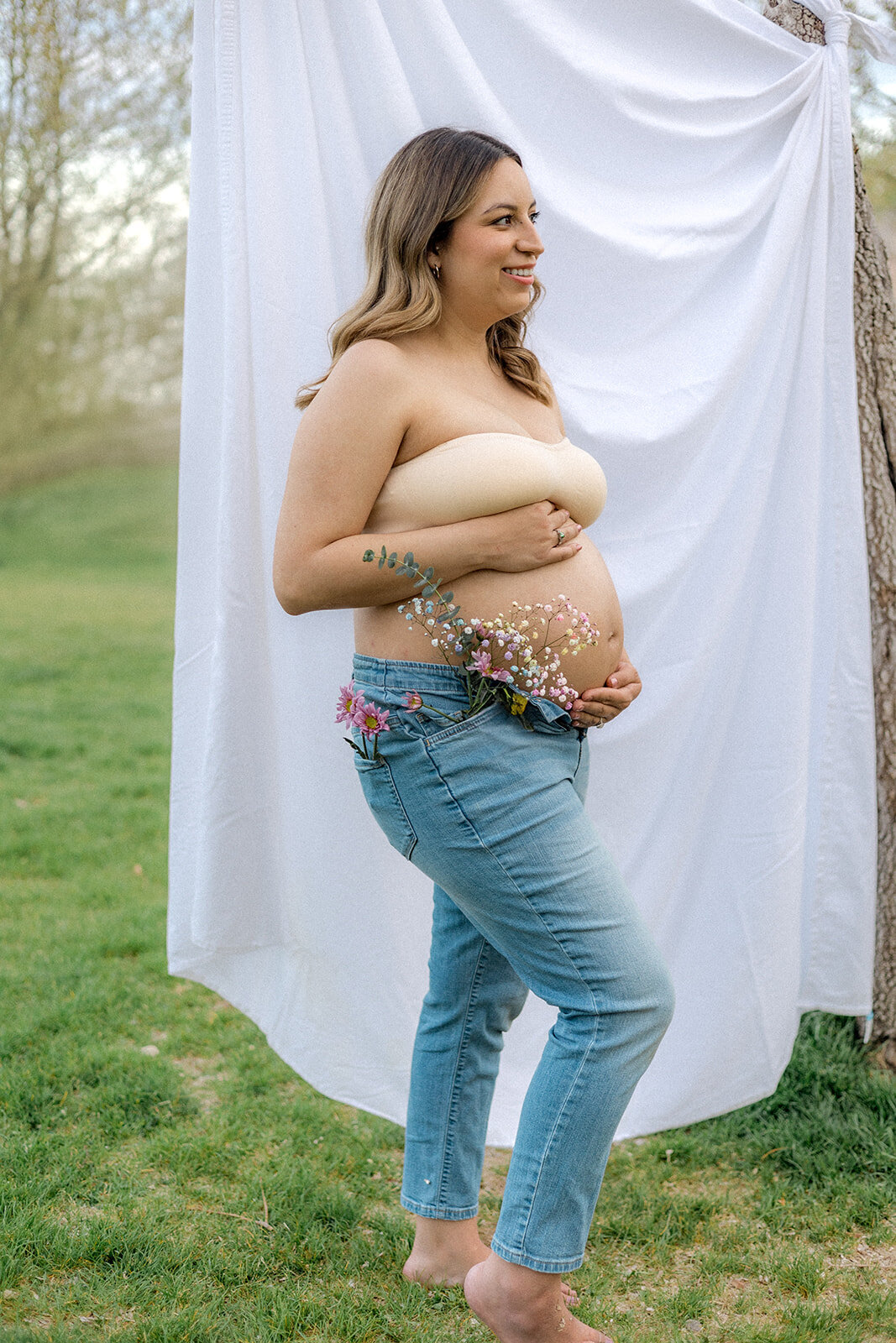 A pregnant woman smiles holding flowers
