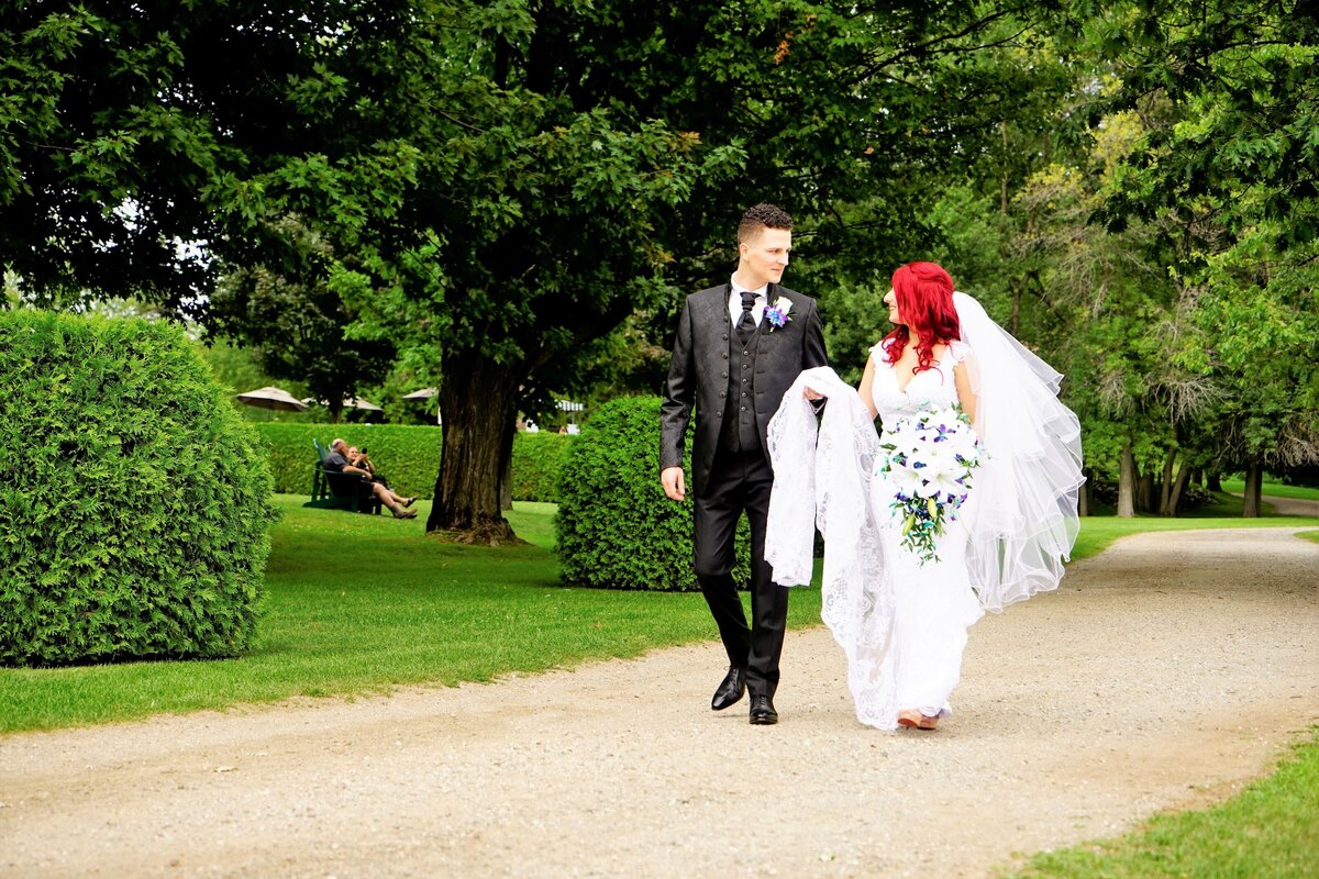 The bride with striking fiery red hair walks hand in hand with the groom. Their coordinated stroll highlights their joyful connection and the bride's unique and vibrant hair color, adding a distinctive and memorable touch to their wedding day.