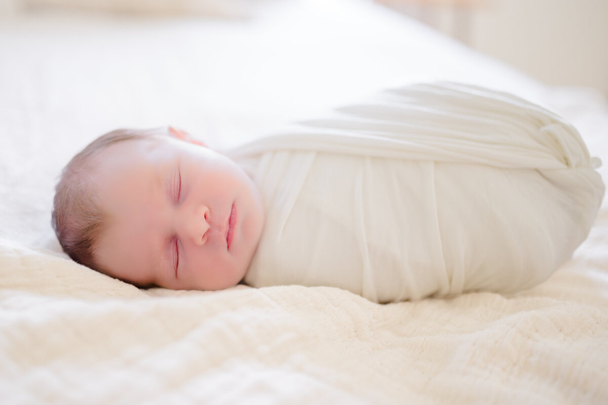 Peaceful image of a sleeping, swaddled newborn, wrapped snugly in a soft blanket. Captured by a Connecticut newborn photographer, this serene moment highlights the baby's delicate features and warmth.
