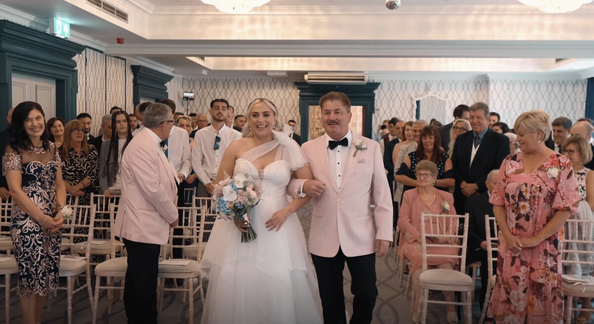 The Bride alks down the aisle. From the Bride and Grooms wedding highlights film shot at Pendley Manor, Hertfordshire by Hertfordshire wedding videographer HC Visuals.