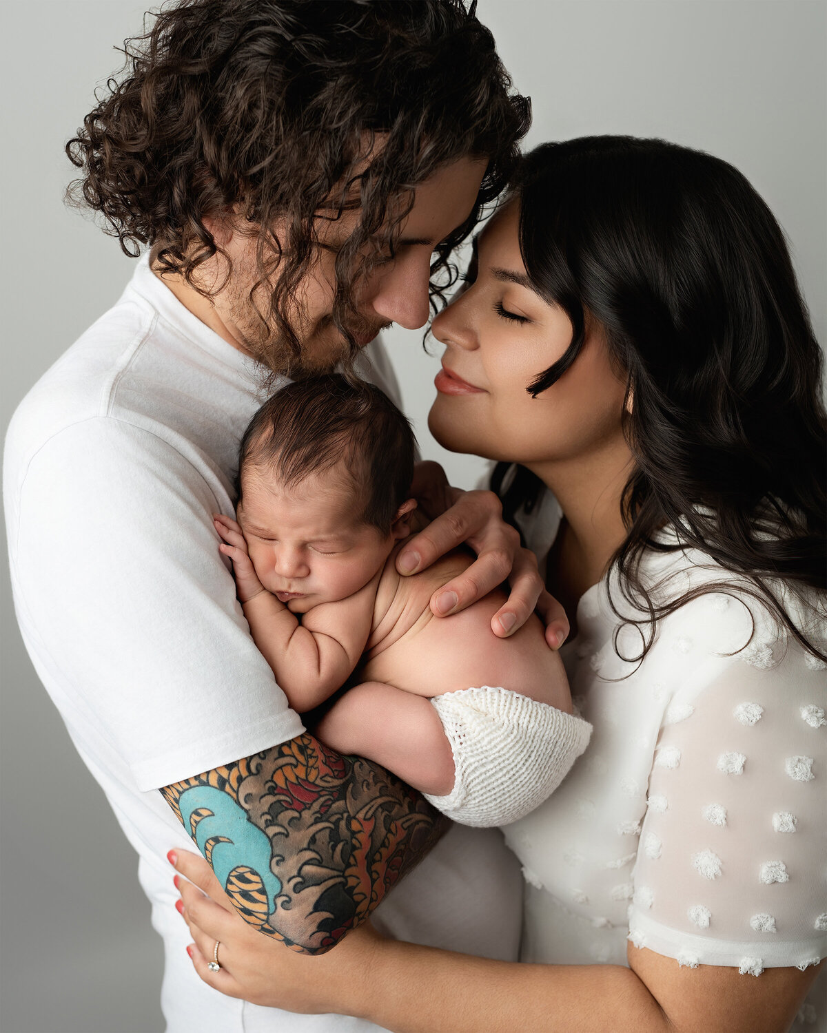 Emotional family studio portrait with parents embracing their newborn baby | Paris Ontario