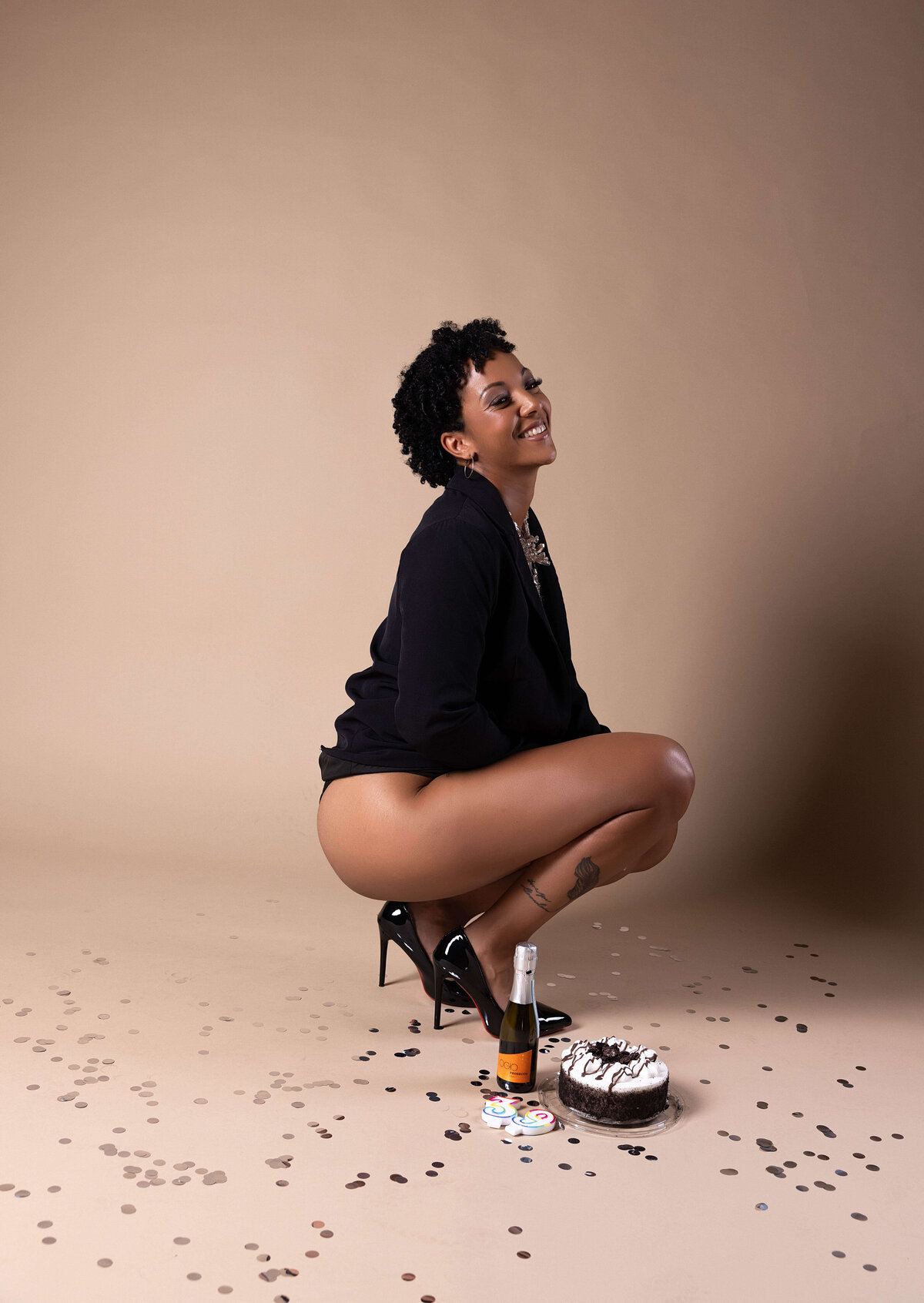 woman crouching next to cake and champagne in birthday session with reva davis photography