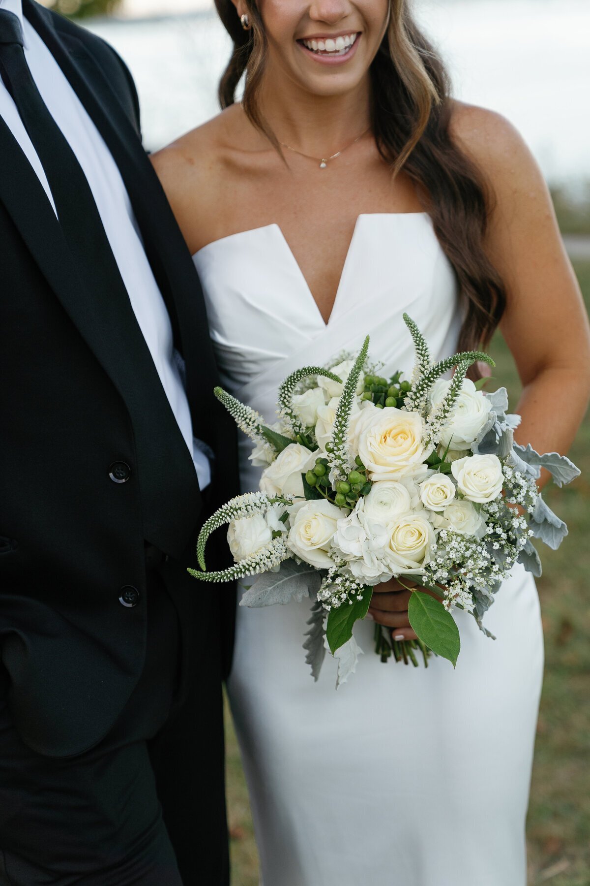 Bride and groom embracing and holding florals taken by wedding film photography business