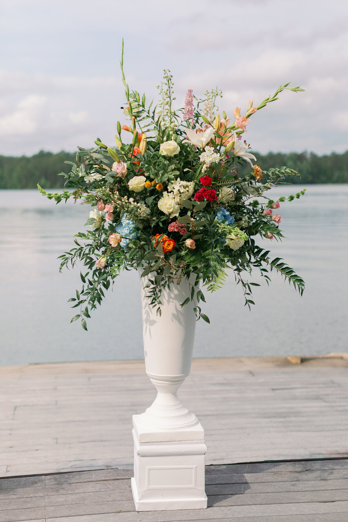 white vase with greenery and colorful flowers coming out