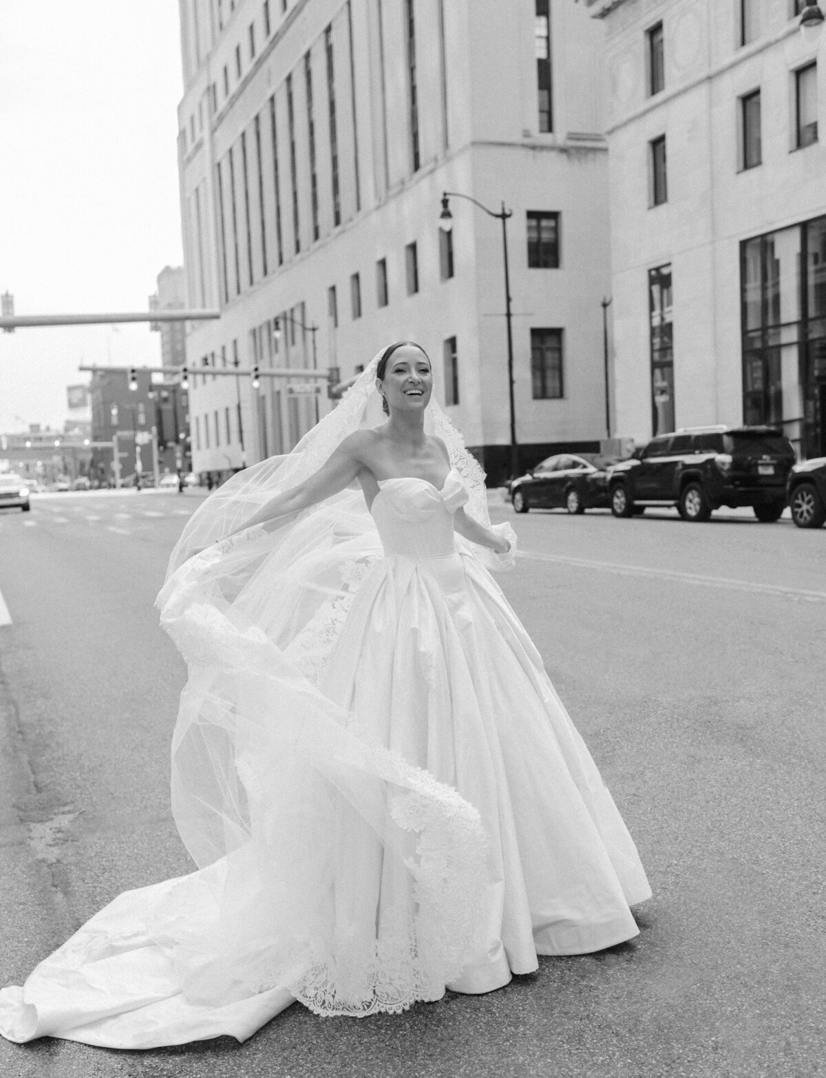 a bride laughs, veil in the wind outside State Savings Bank in Detroit