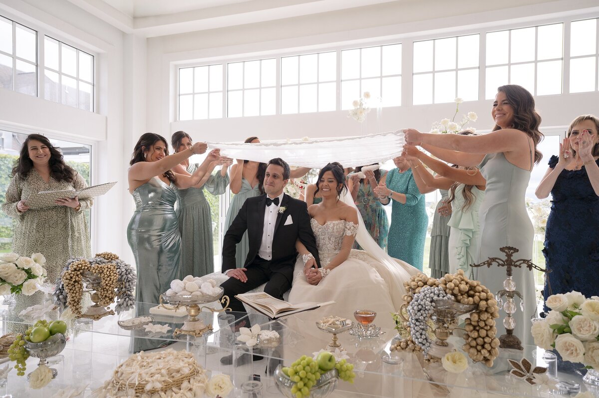 Bride and Groom sit at Sofreh Aghd during Persian wedding ceremony at Belle Mer, Newport.