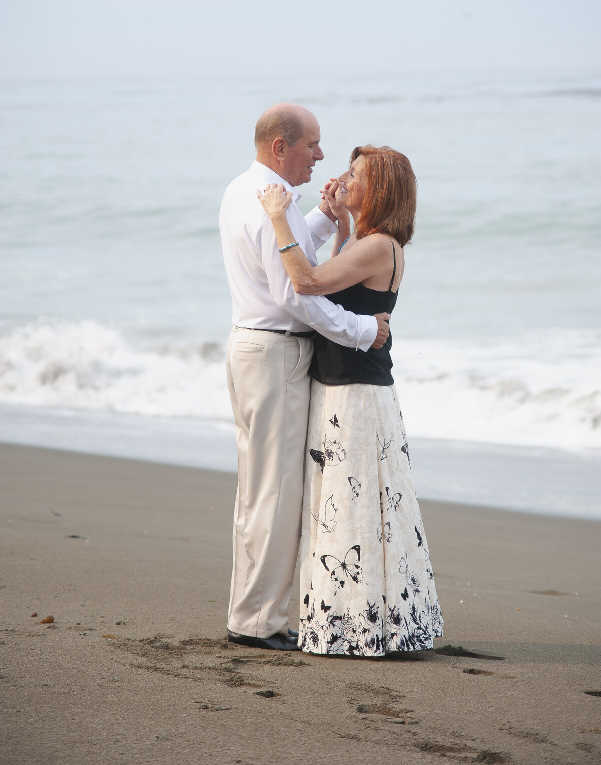 Senior couple dancing on the beach with ocean in the background