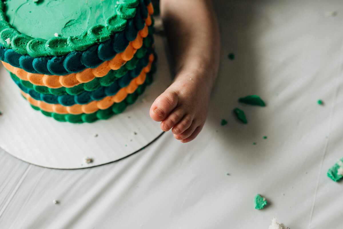 Baby sits on the floor with cake.