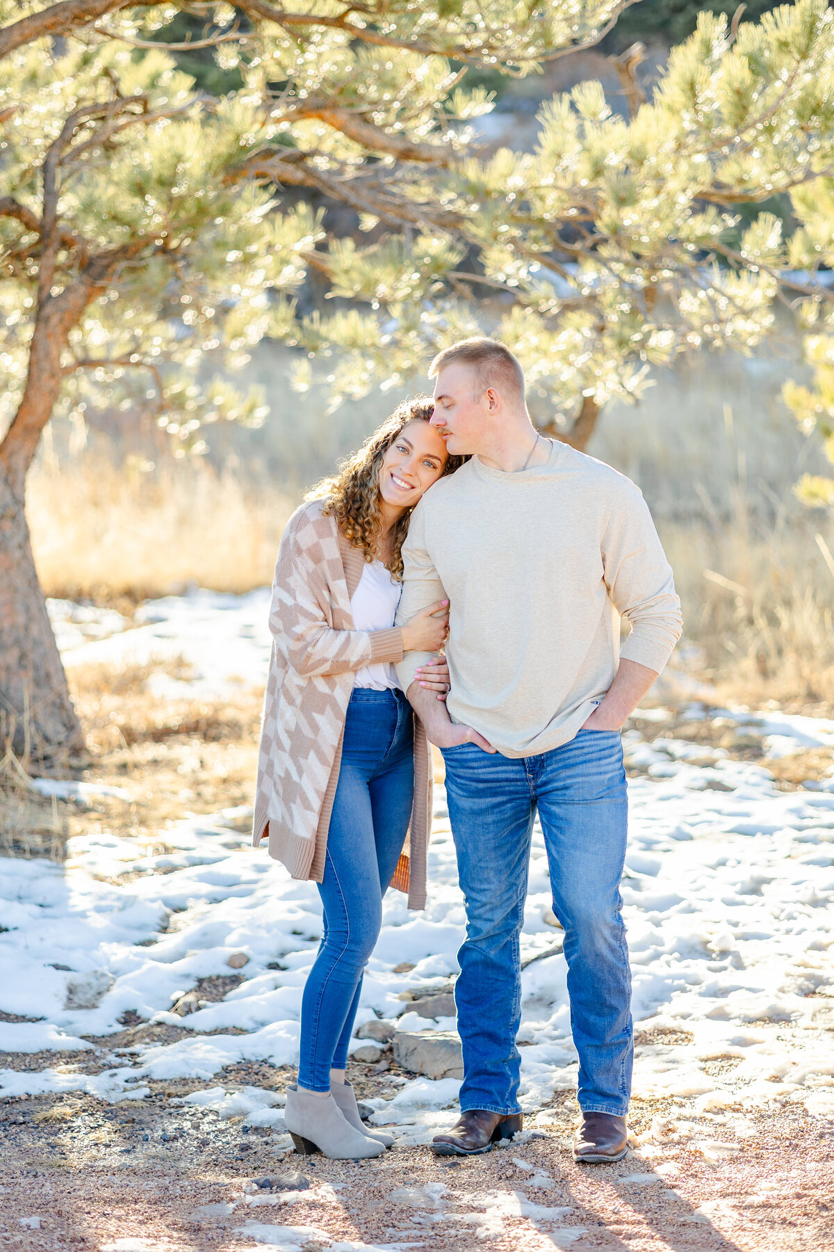 Colorado Springs Engagement Photographer - Couple Standing in snow under a tree.