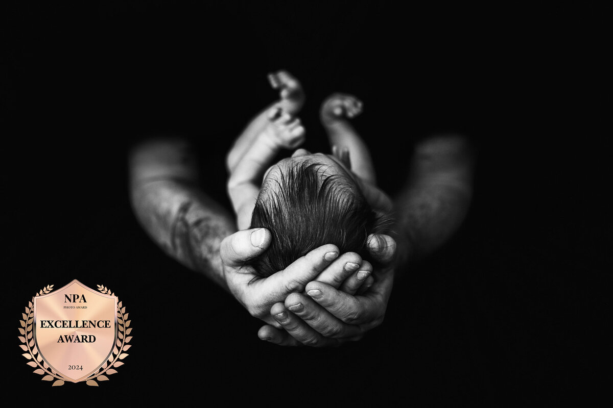 newborn baby cradled in fathers hands in traverse city