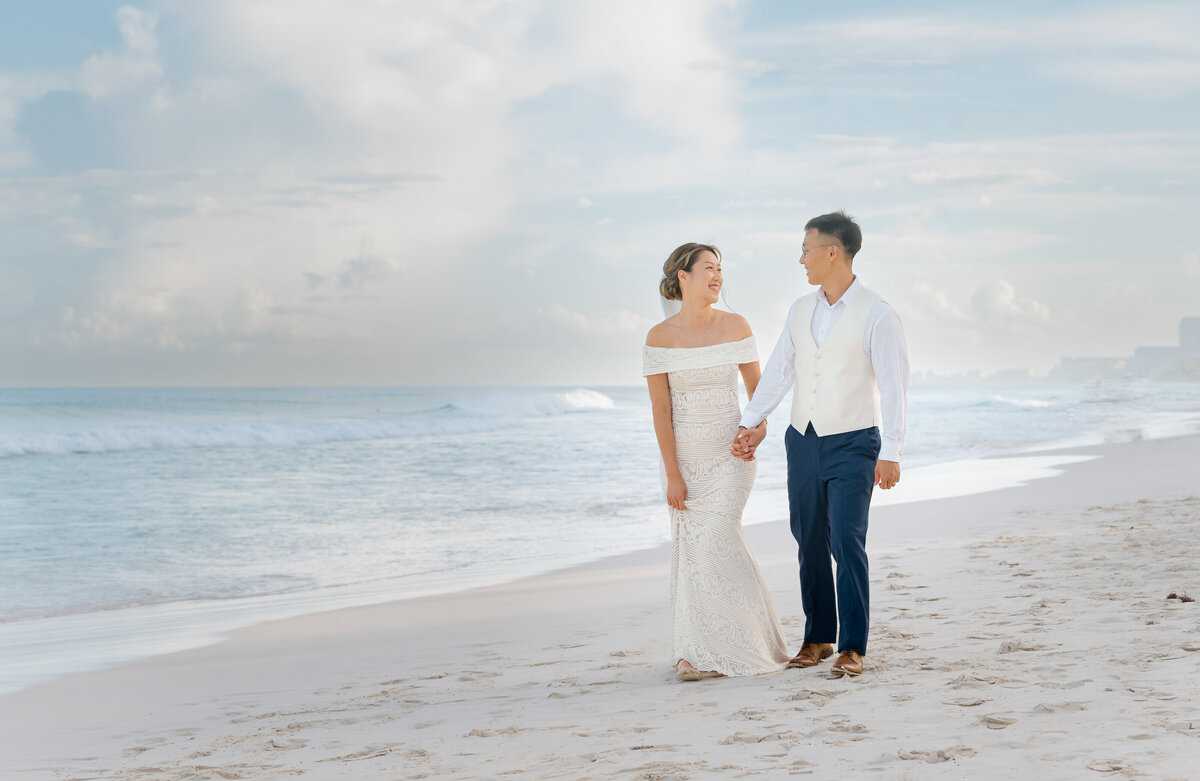 a bride and groom walkign on the beach in Cancun