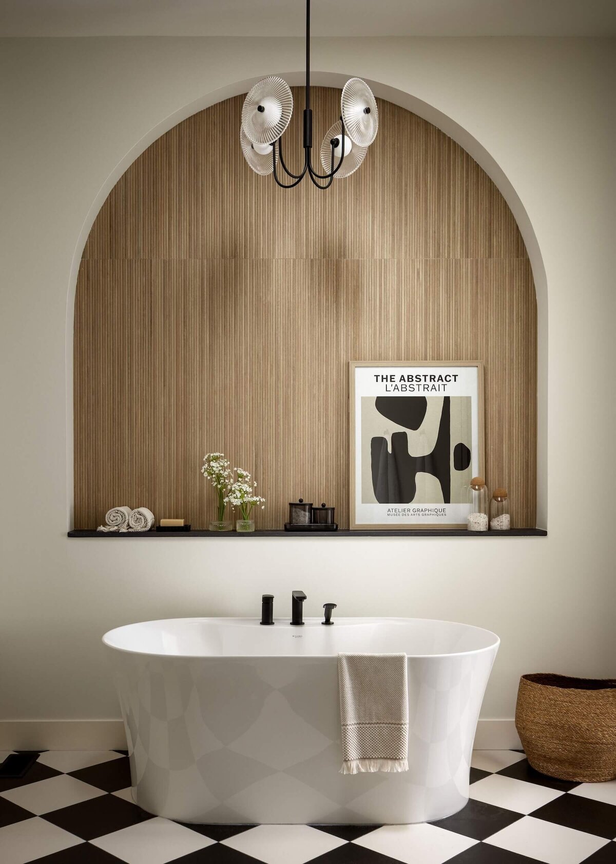 Luxurious ensuite featuring a fluted tile arch, elegant glass pendant lighting, a freestanding soaker tub, and a sleek Dekton ledge