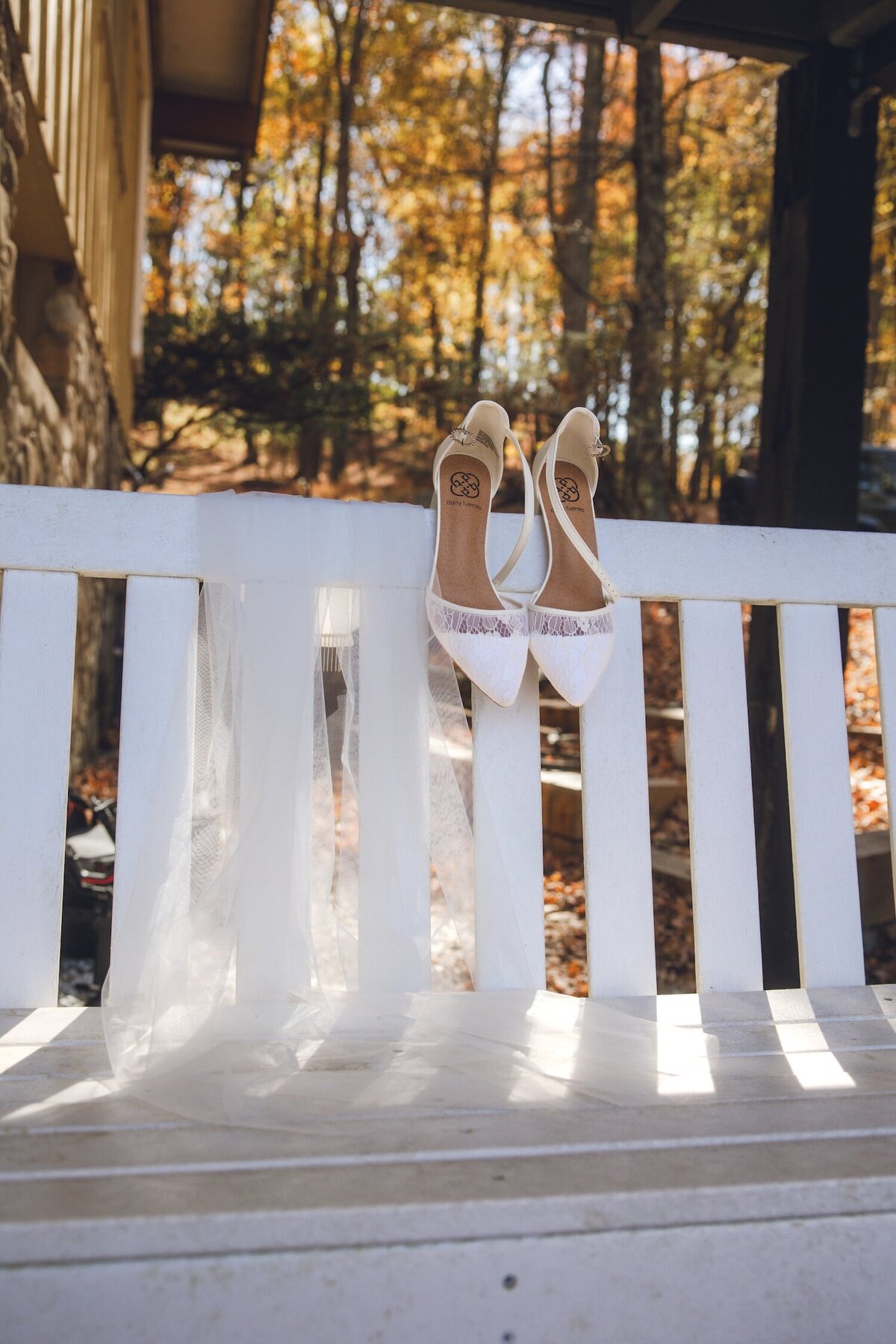 Bridal shoes and veil hanging on a white bench outside a cabin in New Jersey.
