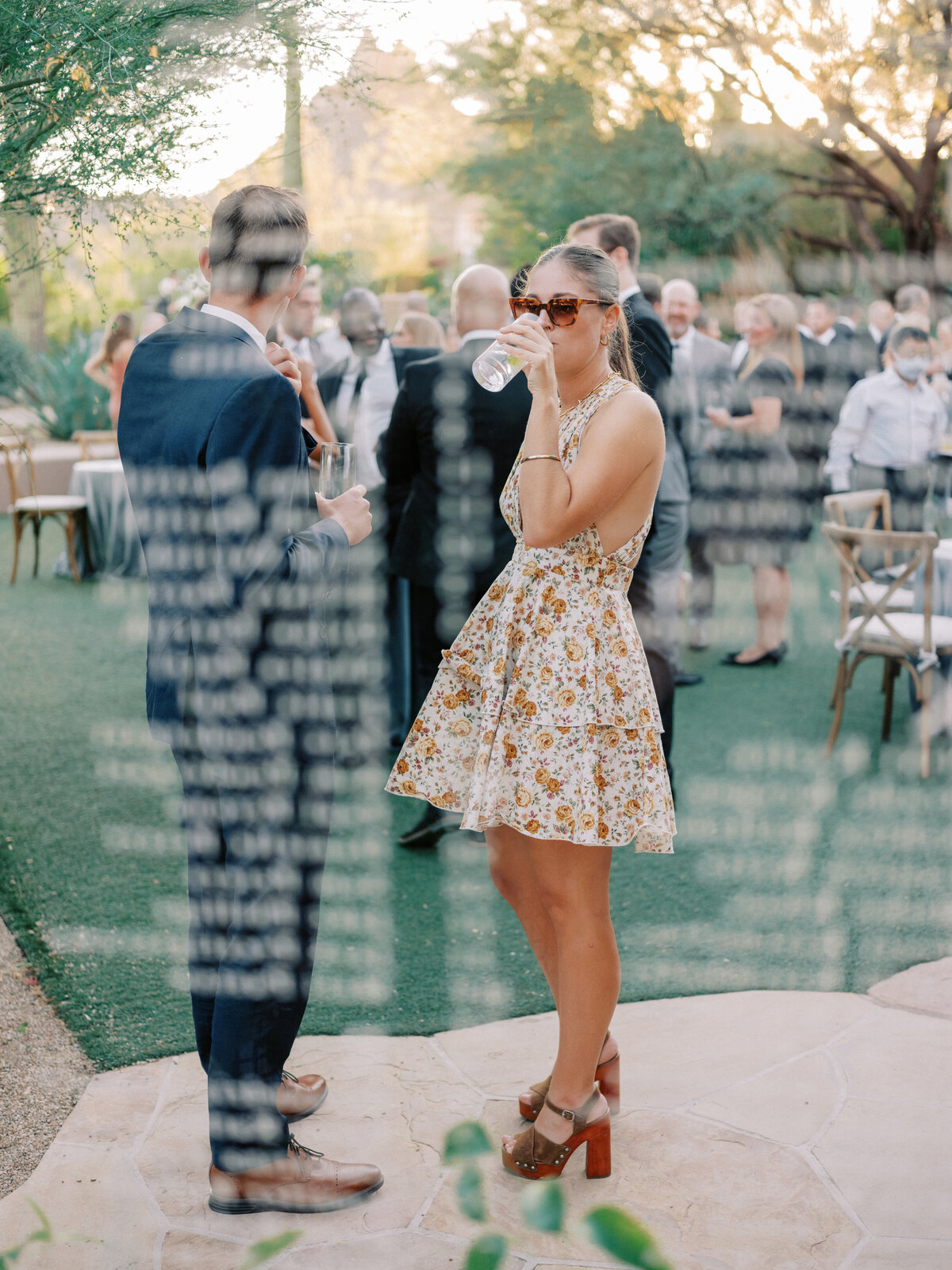 A stylish outdoor wedding reception with guests enjoying cocktails in a breathtaking desert venue. The perfect mix of elegance and celebration under the golden sunset sky.