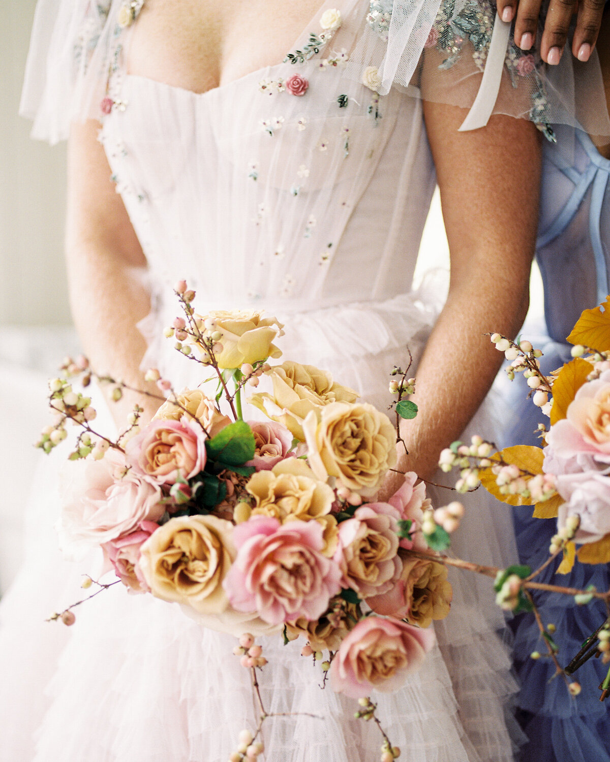 A close up of a bouquet with romantic florals with blush and yellow roses