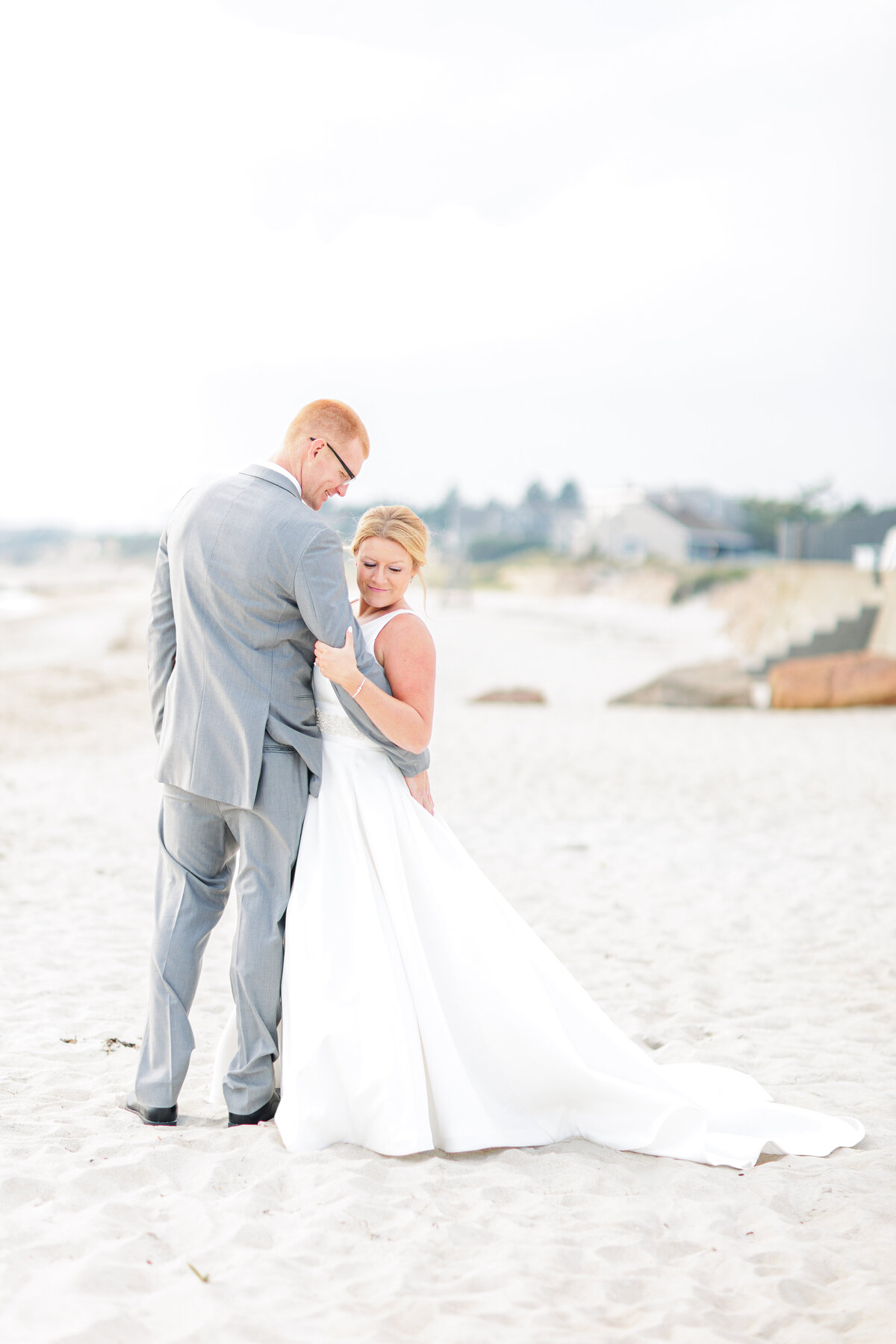A groom hugging his bride on the beach representing Cape Cod wedding pictures