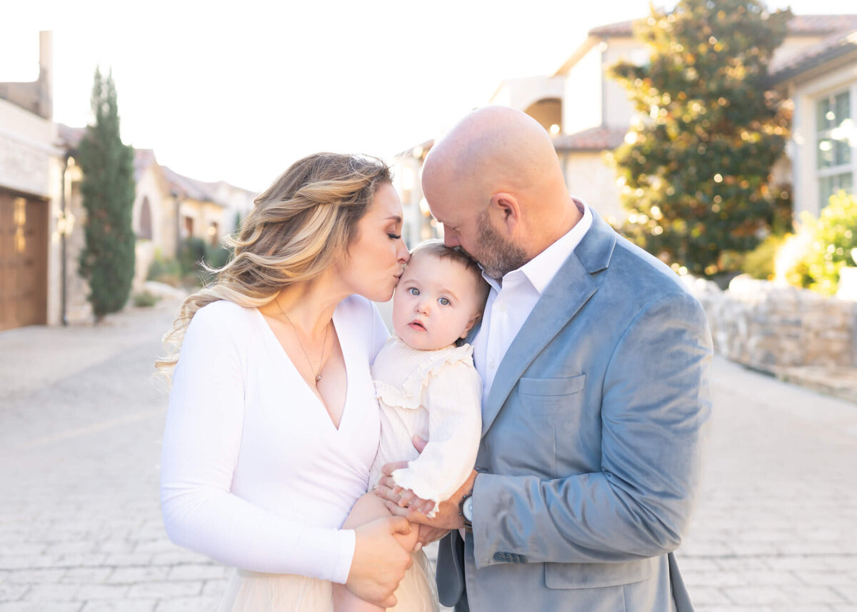 mom and dad kissing baby outdoors in Adriatica McKinney