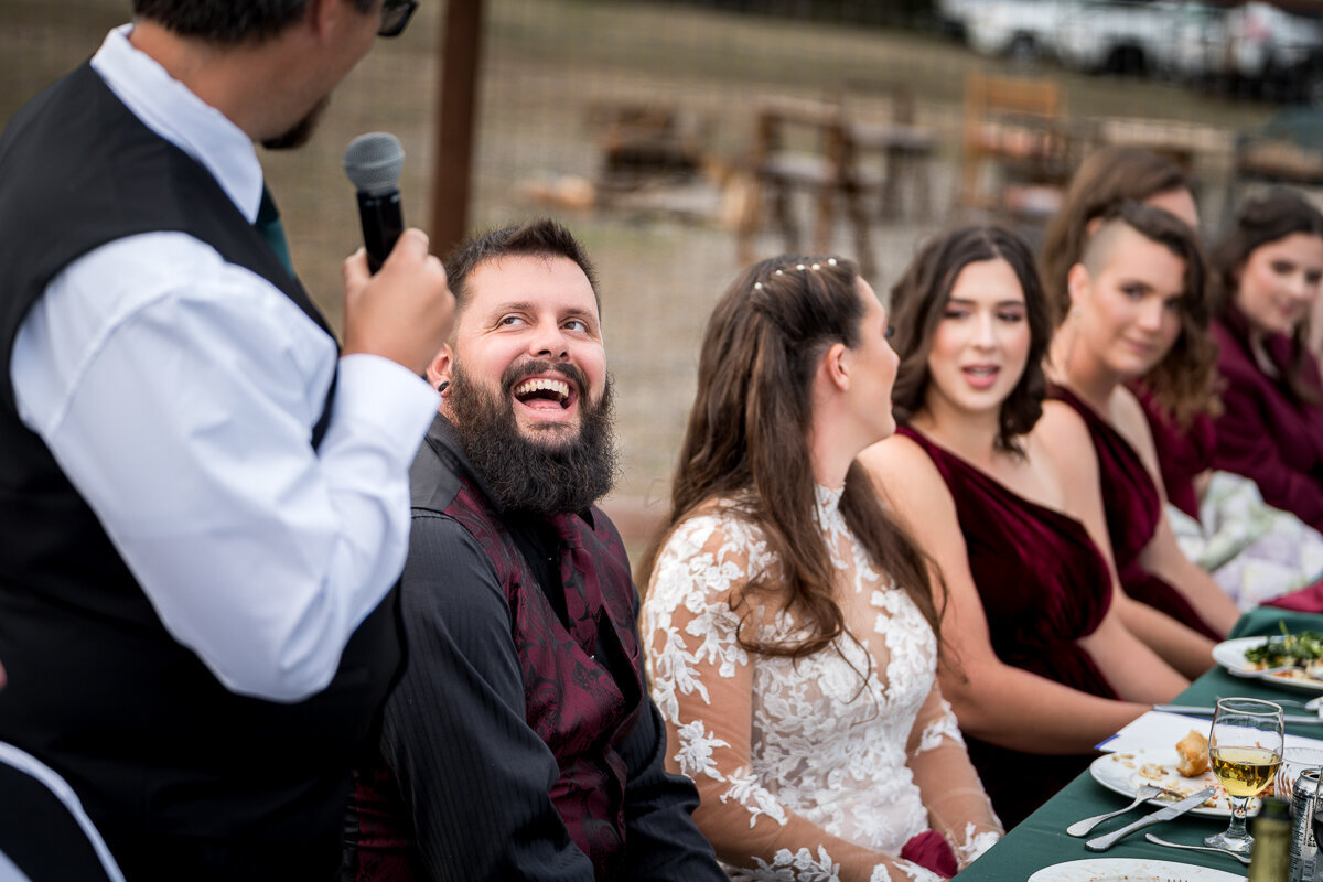 A candid moment as the groom bursts into laughter during his best man's heartfelt and humorous toast at the rustic North Coast Hitching Post in Loleta. The perfect blend of emotion and joy on this unforgettable day!