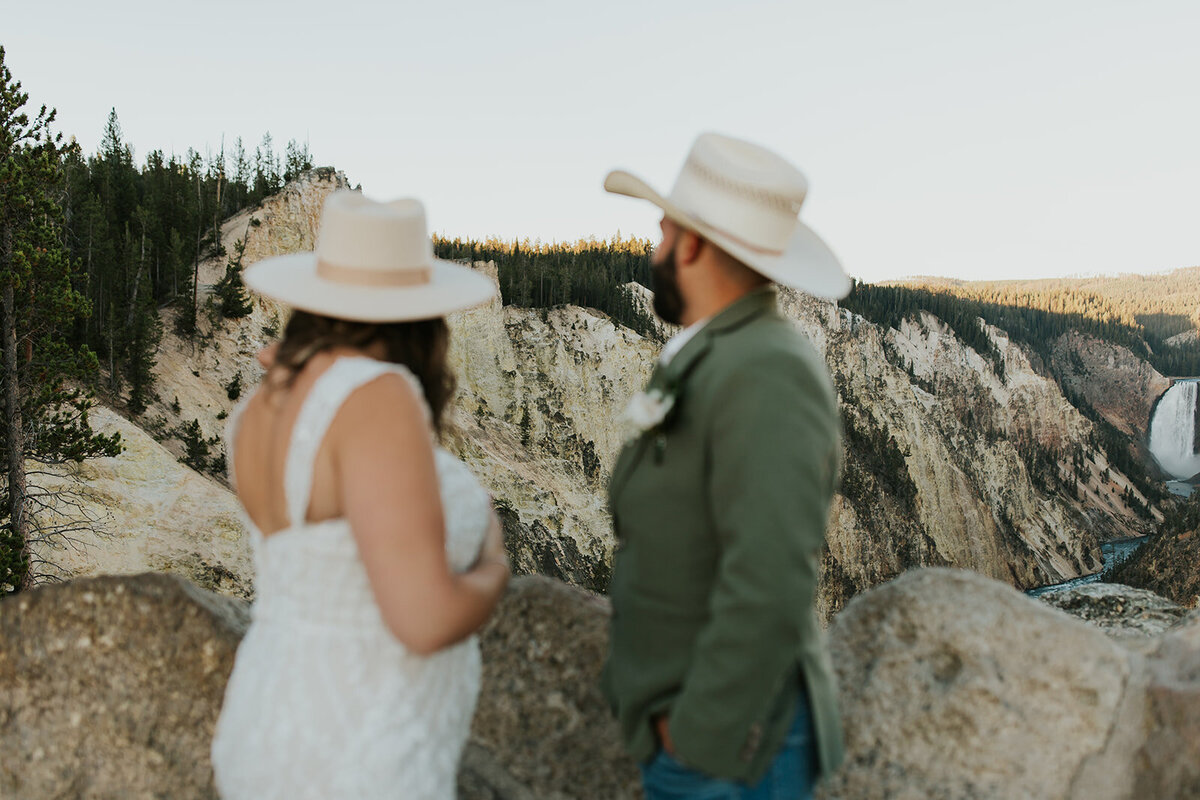 A bride and groom dance together outside in Grand Teton National Park. She has her hand on his shoulder and he has his hand on her waist. Their eyes are closed at each other, foreheads touching. Trees are behind them.