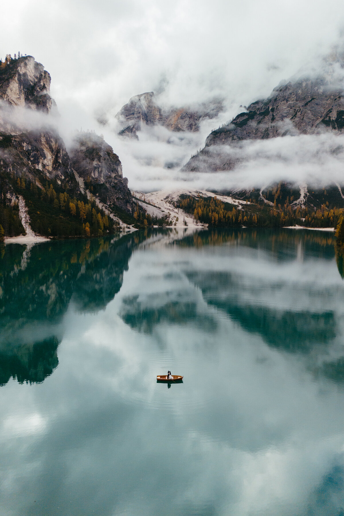 Single rowboat on calm Lago di Braies reflecting mountains