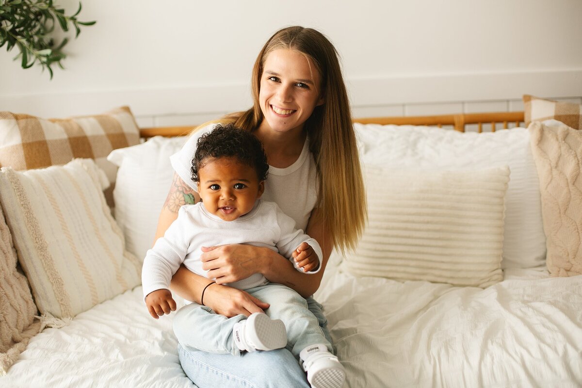 A-happy-baby-sitting-with-his-loving-mom-during-a-milestone-photo-session-at-studio-1432-in-speedway-indiana-capturing-a-special-bond-in-a-cozy-studio-setting