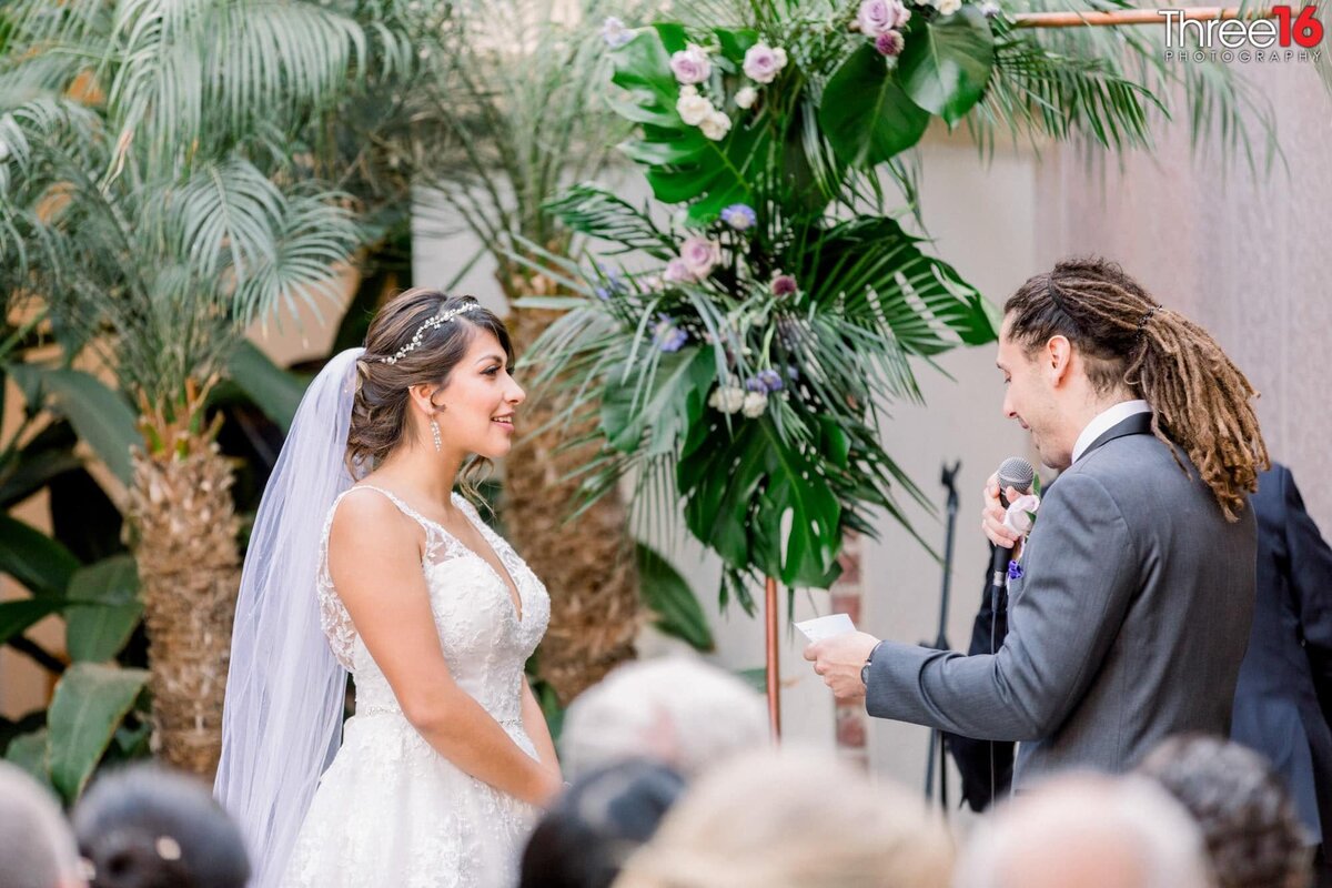 Bride smiles as her Groom reads her his vows
