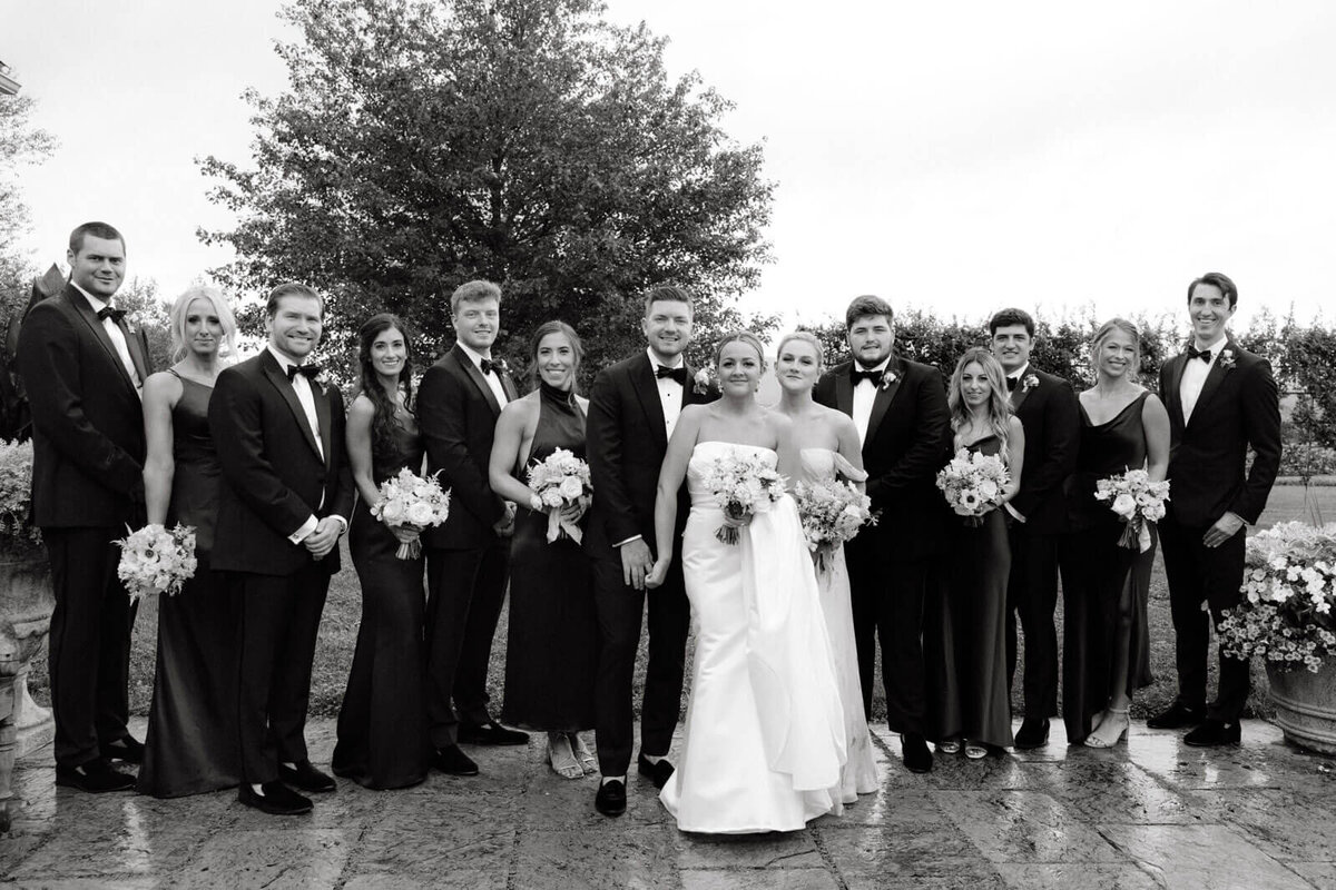 The bride, groom, bridesmaids, and groomsmen are elegantly standing outdoors at The Lion Rock Farm, Sharon, CT. Image by Jenny Fu Studio