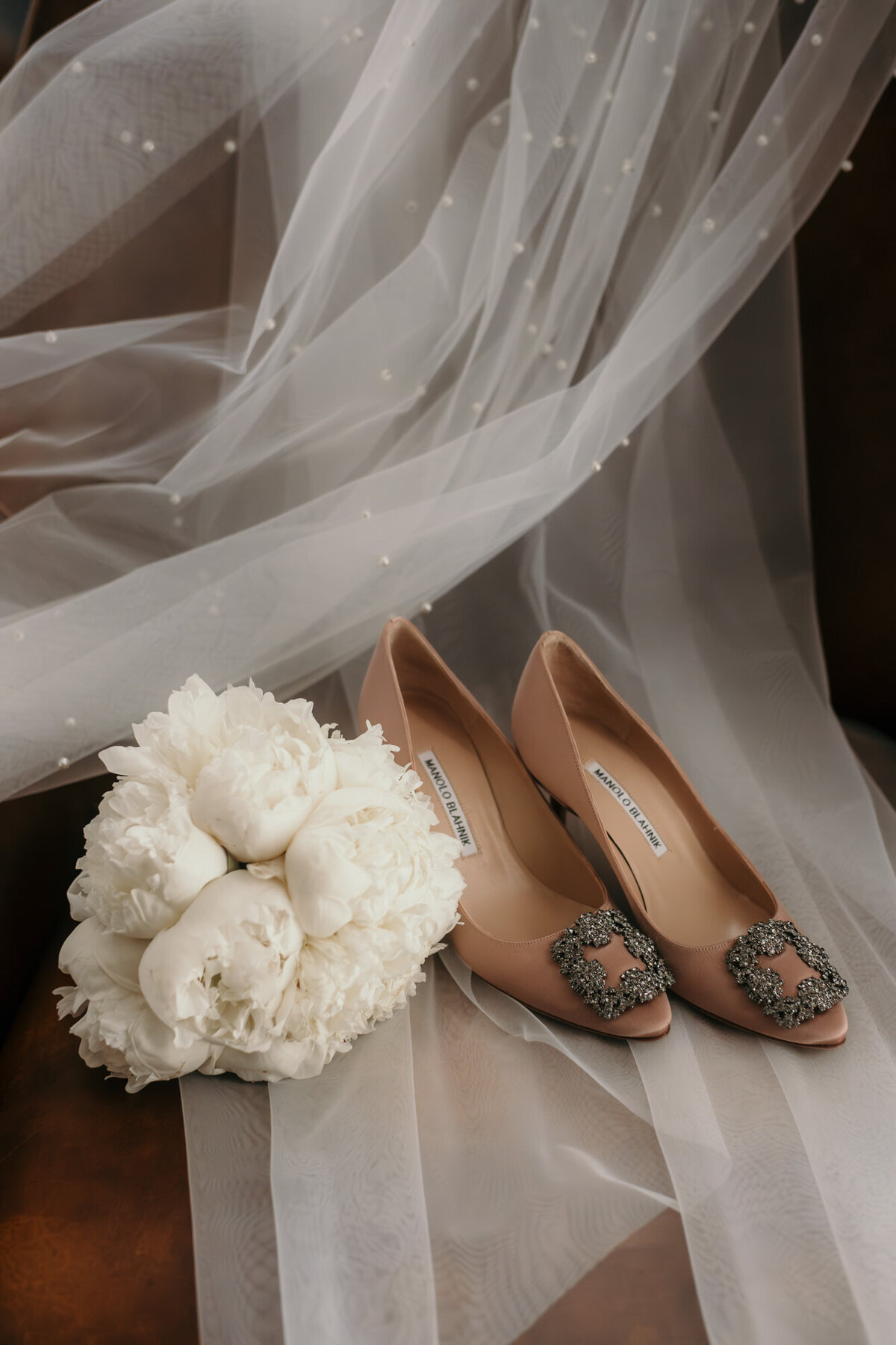 Brautstrauß, Brautschuhe sowie Schleier liegen schön drapiert bereit für den großen Tag.
