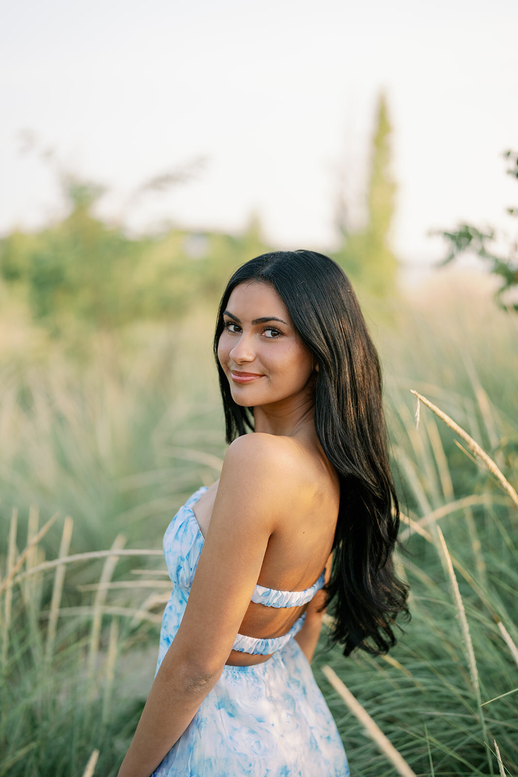 Senior girl posing in tall dune grass during golden hour at South Haven North Beach.