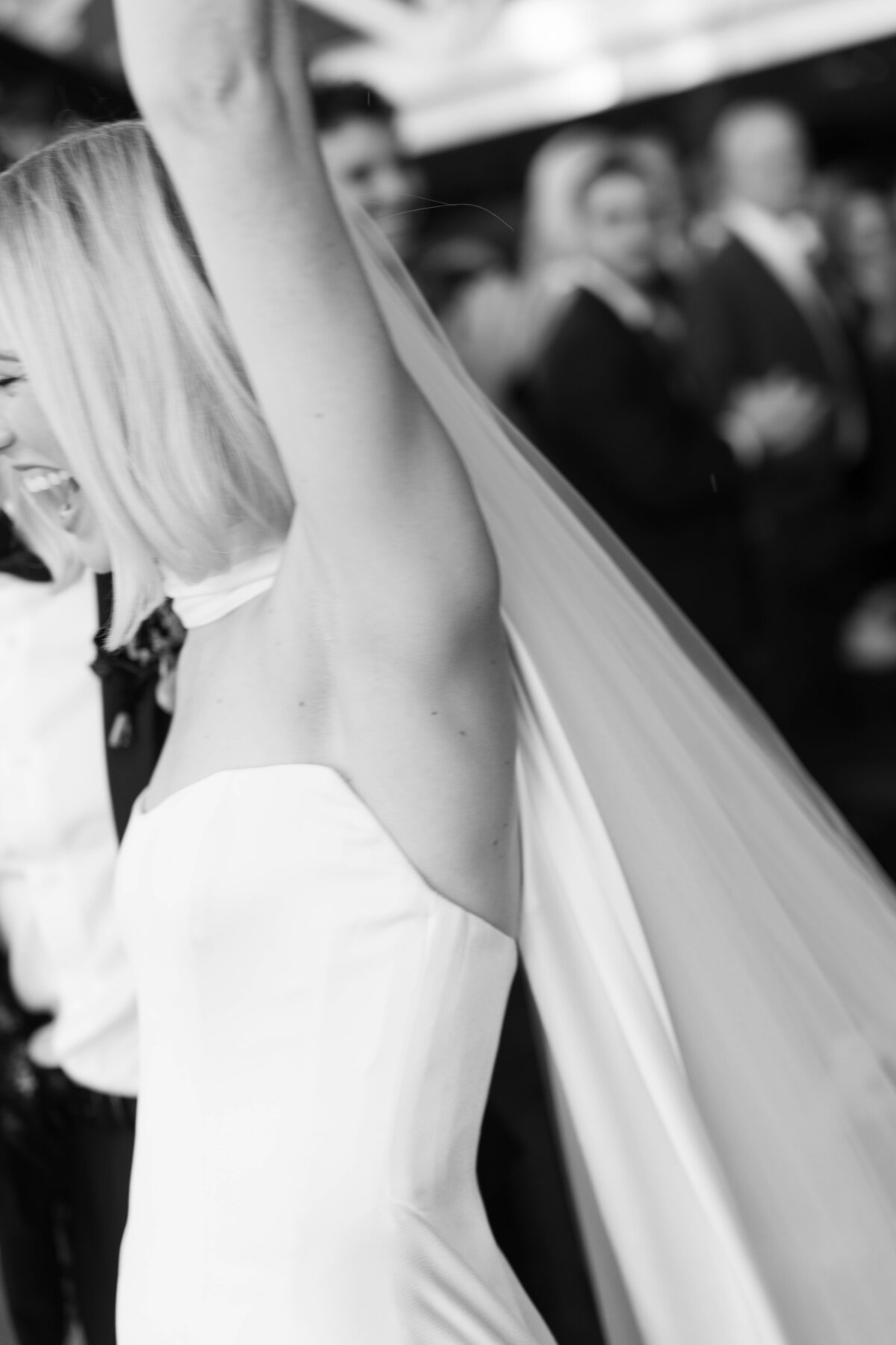 Black and white candid of bride celebrating with arm raised during wedding reception