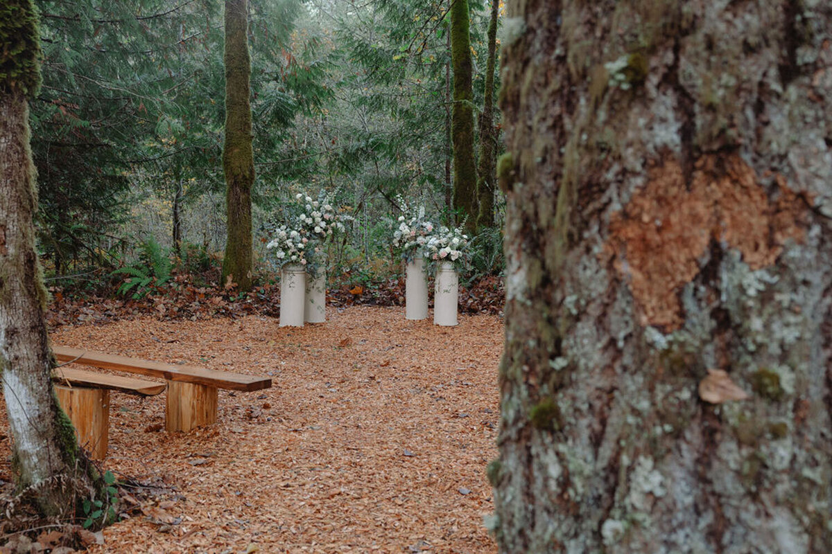 Outdoor ceremony site with wooden benches and floral arrangements