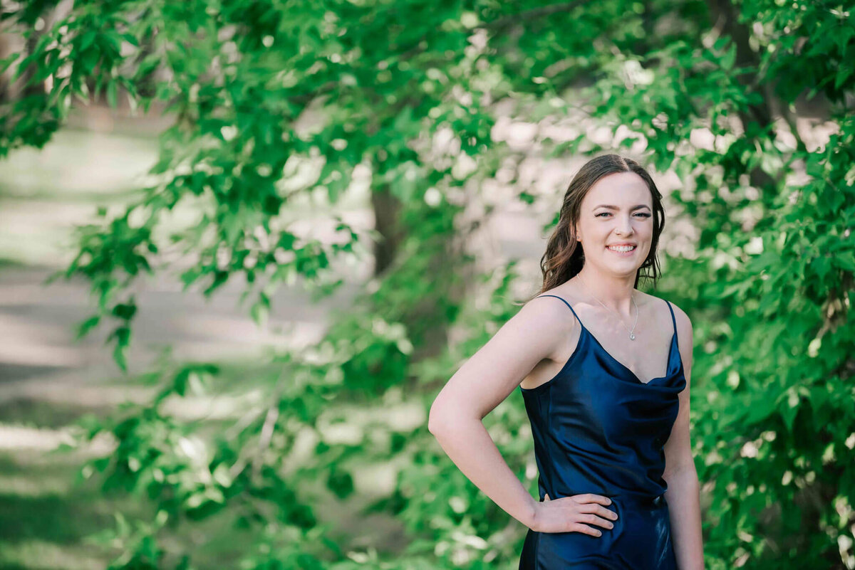 A young brunette girl standing by some trees