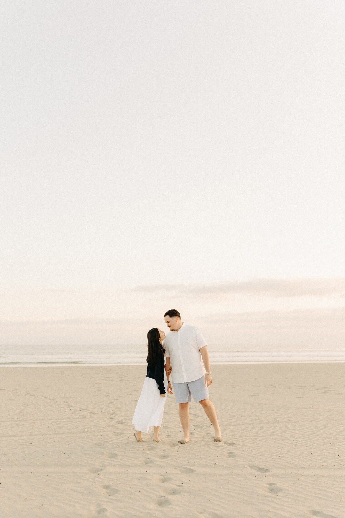 Couple walking hand in hand on Coronado Beach during golden hour