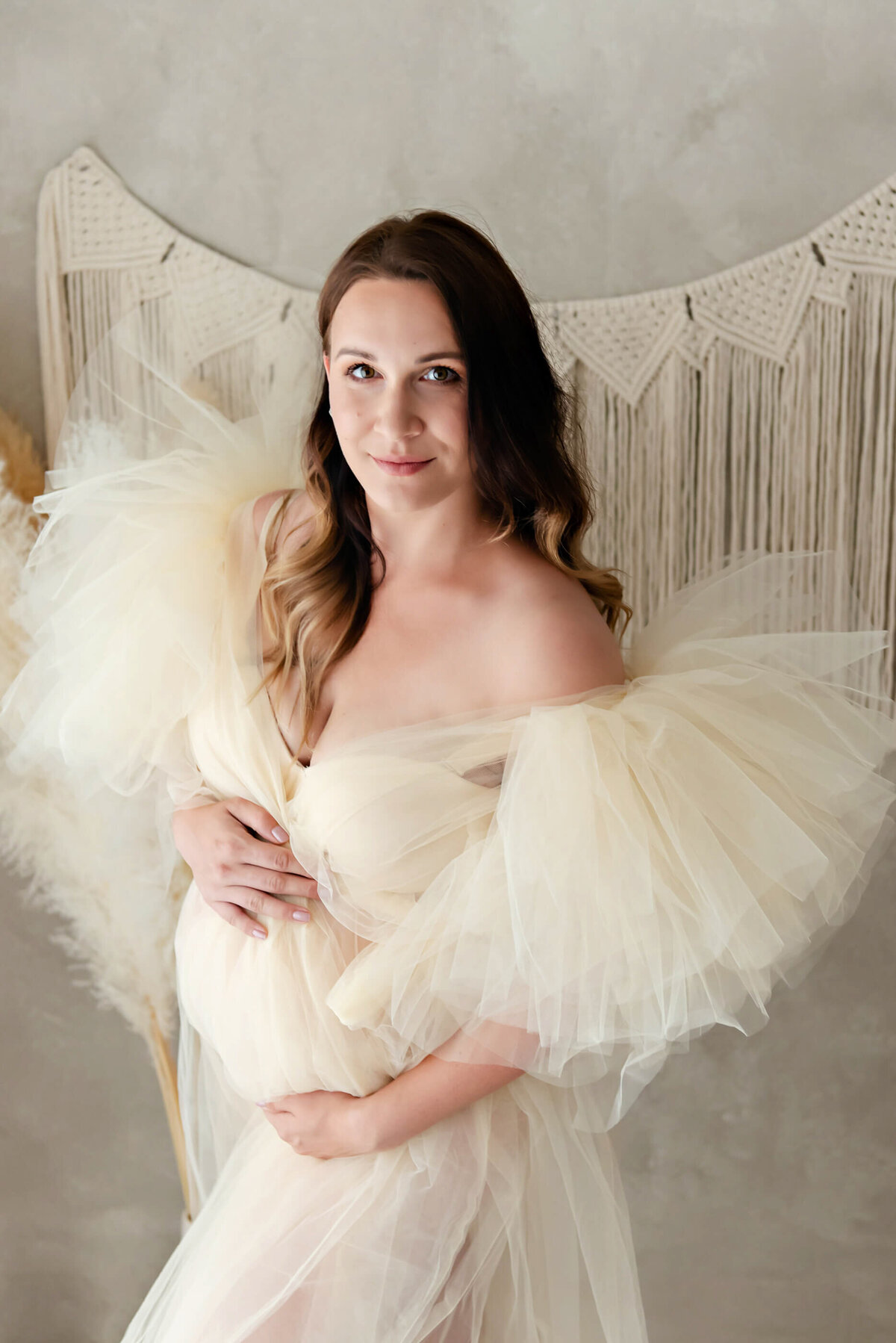 woman wearing a beige maternity dress in studio for her maternity photos in Burlington, ON