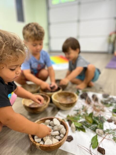 Toddlers sorting stones and natural materials in wooden bowls at ROOTS Nature Preschool