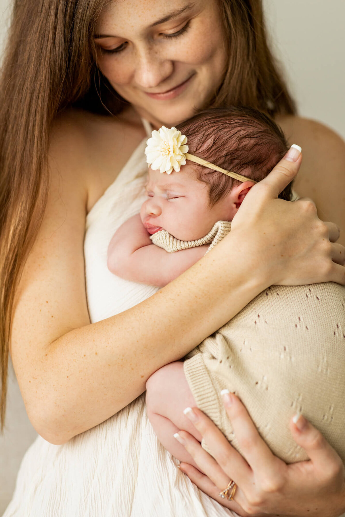 Mom in cream boho dress holding and cuddling her newborn baby in a cream bubble