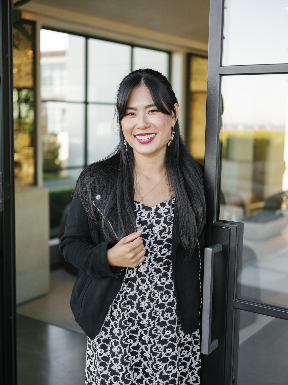 Close-up of smiling woman in patterned dress with black jacket during NYC brand photography session.