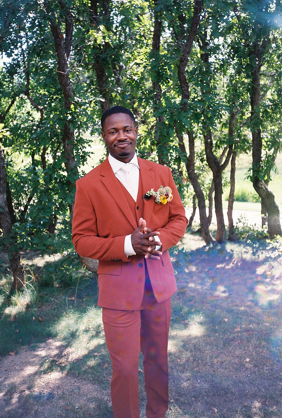 Groom adjusting his tie before his Colorado wedding, photographed in a natural, unposed style on film.