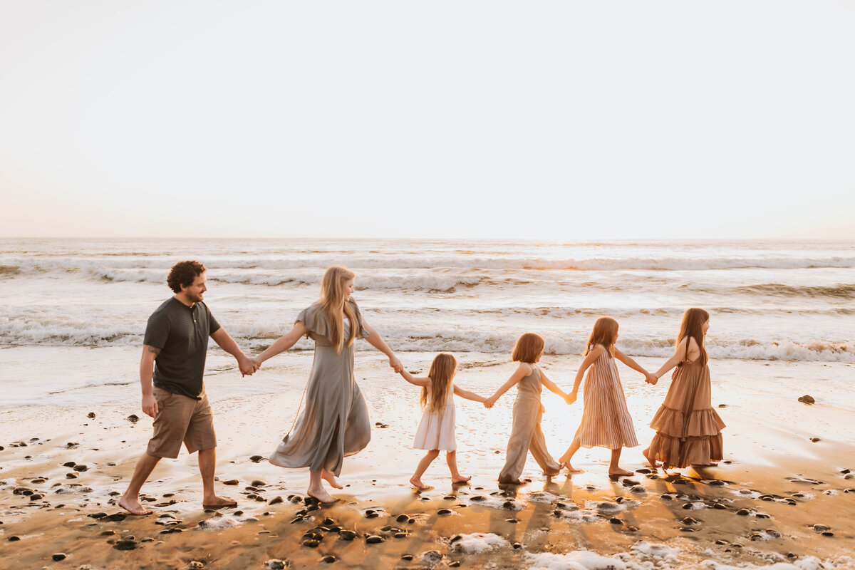 Family of 6 walking in a line holding hands at the beach