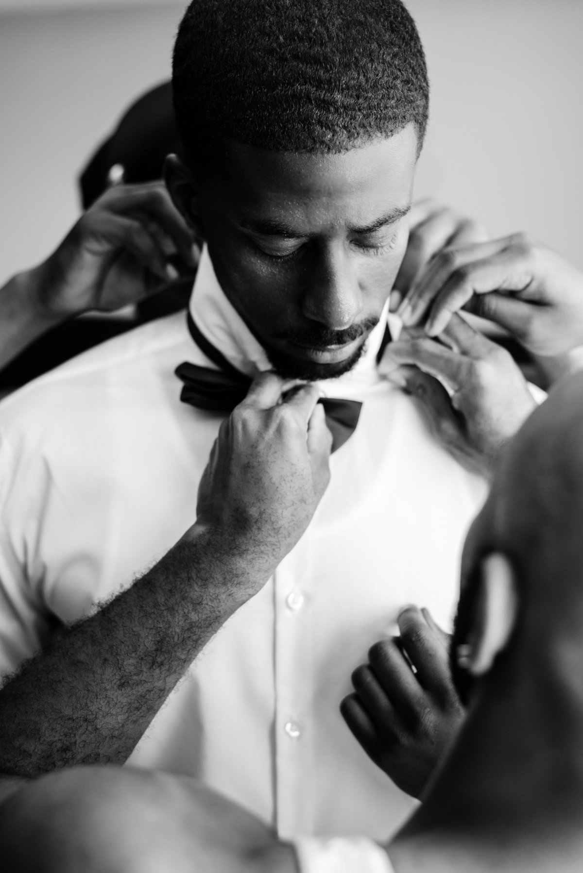 Groom getting some extra help putting his shirt and tie on from his Groomsmen