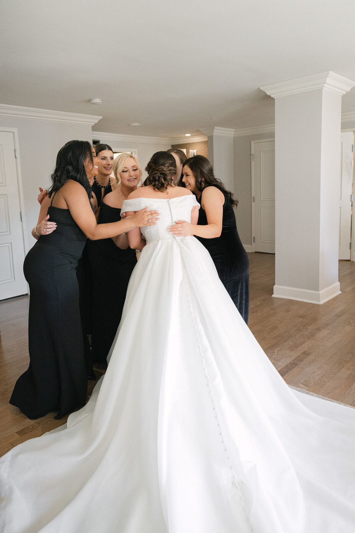 bridesmaids hugging the bride after the first look at The Adolphus in Dallas, capturing a joyful and heartfelt wedding moment at the venue.