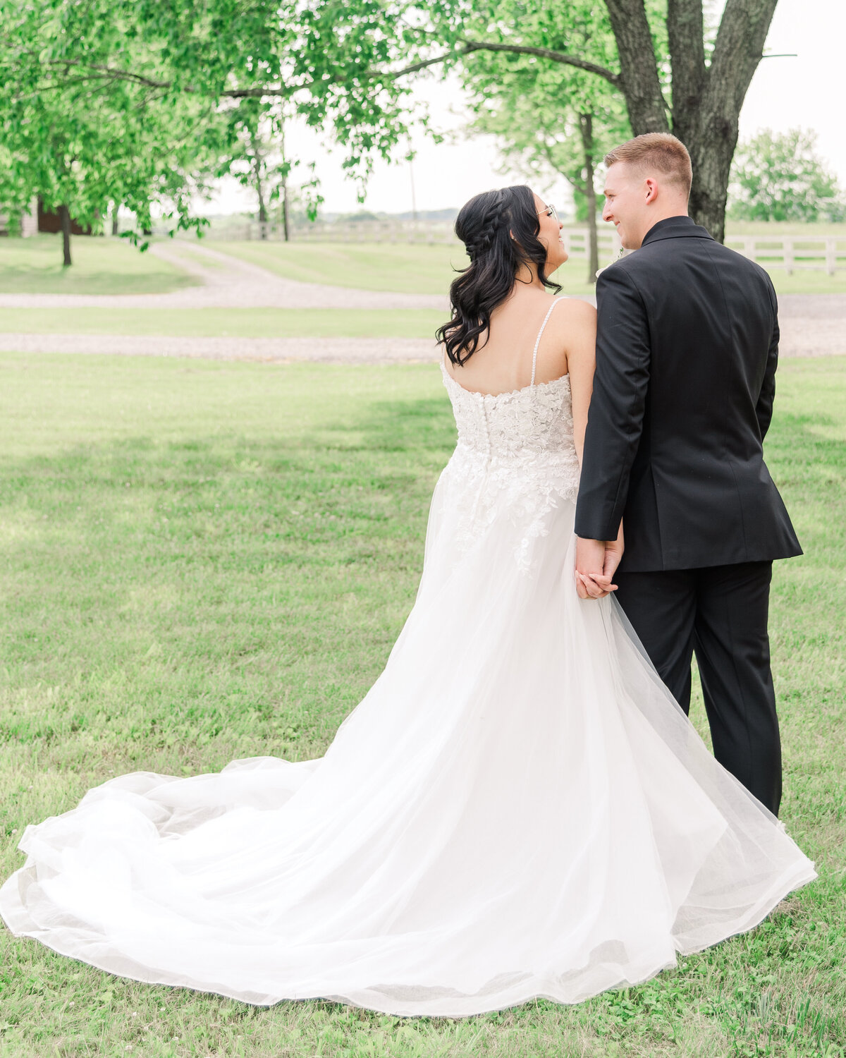 bride and groom looking at each other while showing off the back of her dress at the Farmstead in Harrodsburg