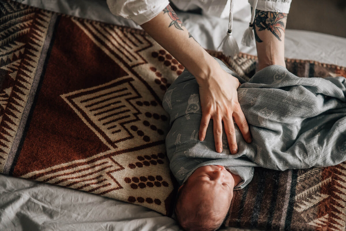 An photo of a baby being swaddled by his mother during a session with Minneapolis newborn photographer, Kate Simpson.