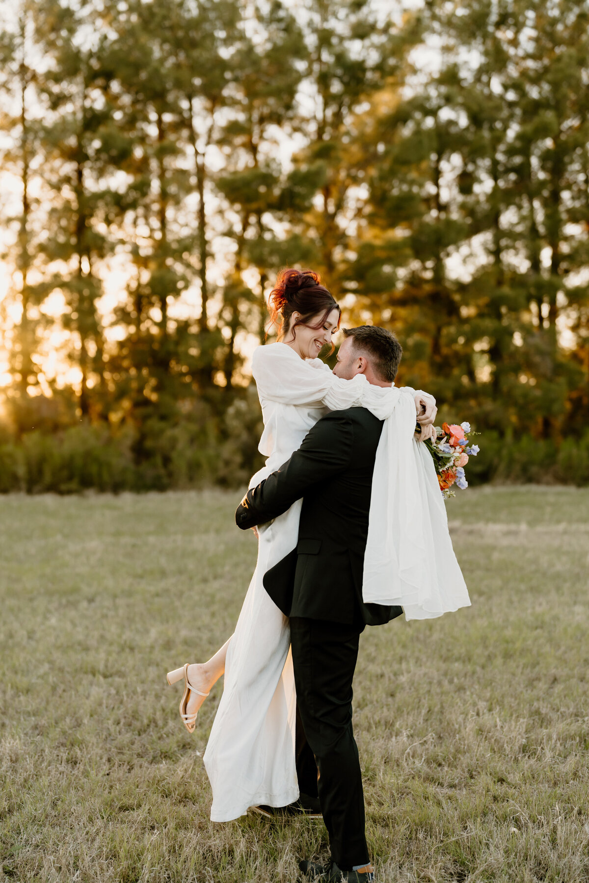 Bride and groom in a field where the bride is getting picked up