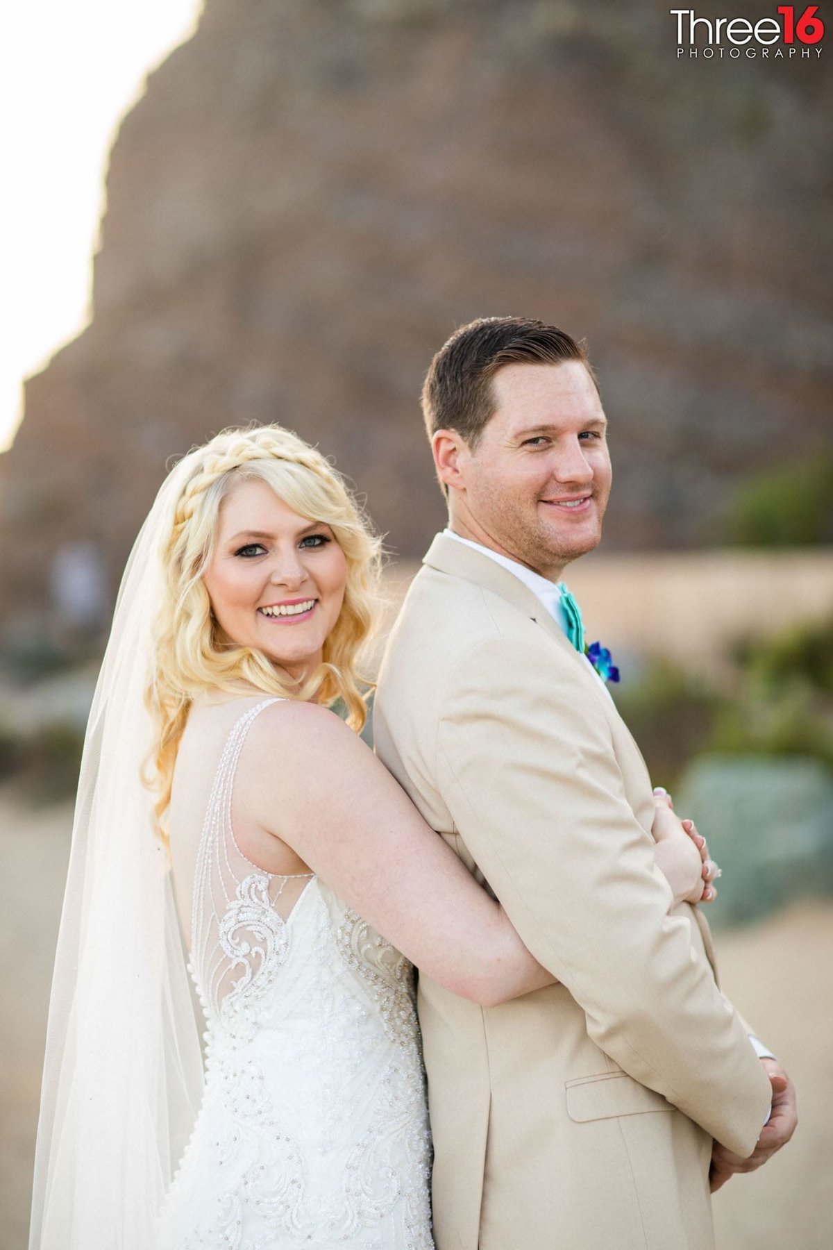 Bride embraces her Groom from behind as they smile for the wedding photographer