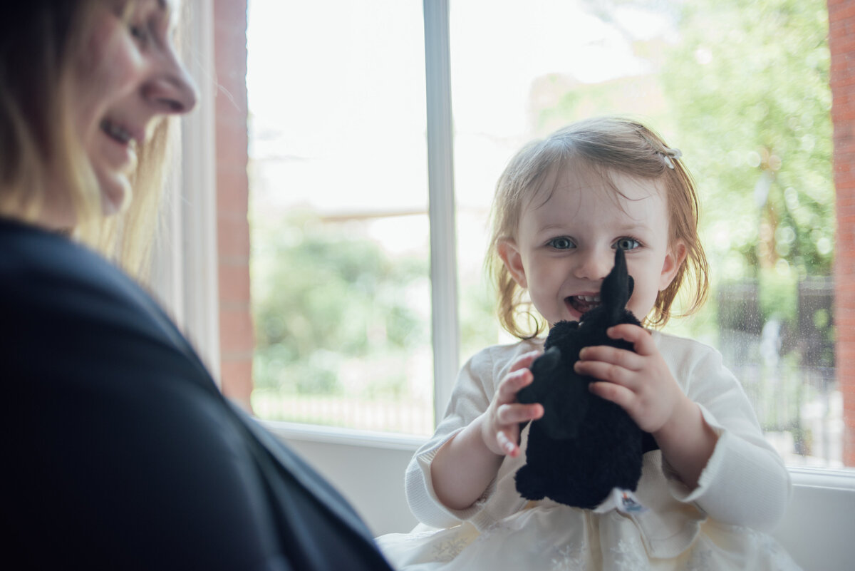 A young girl smiling and holding a toy  taken by London Wedding Photographer Liberty Pearl