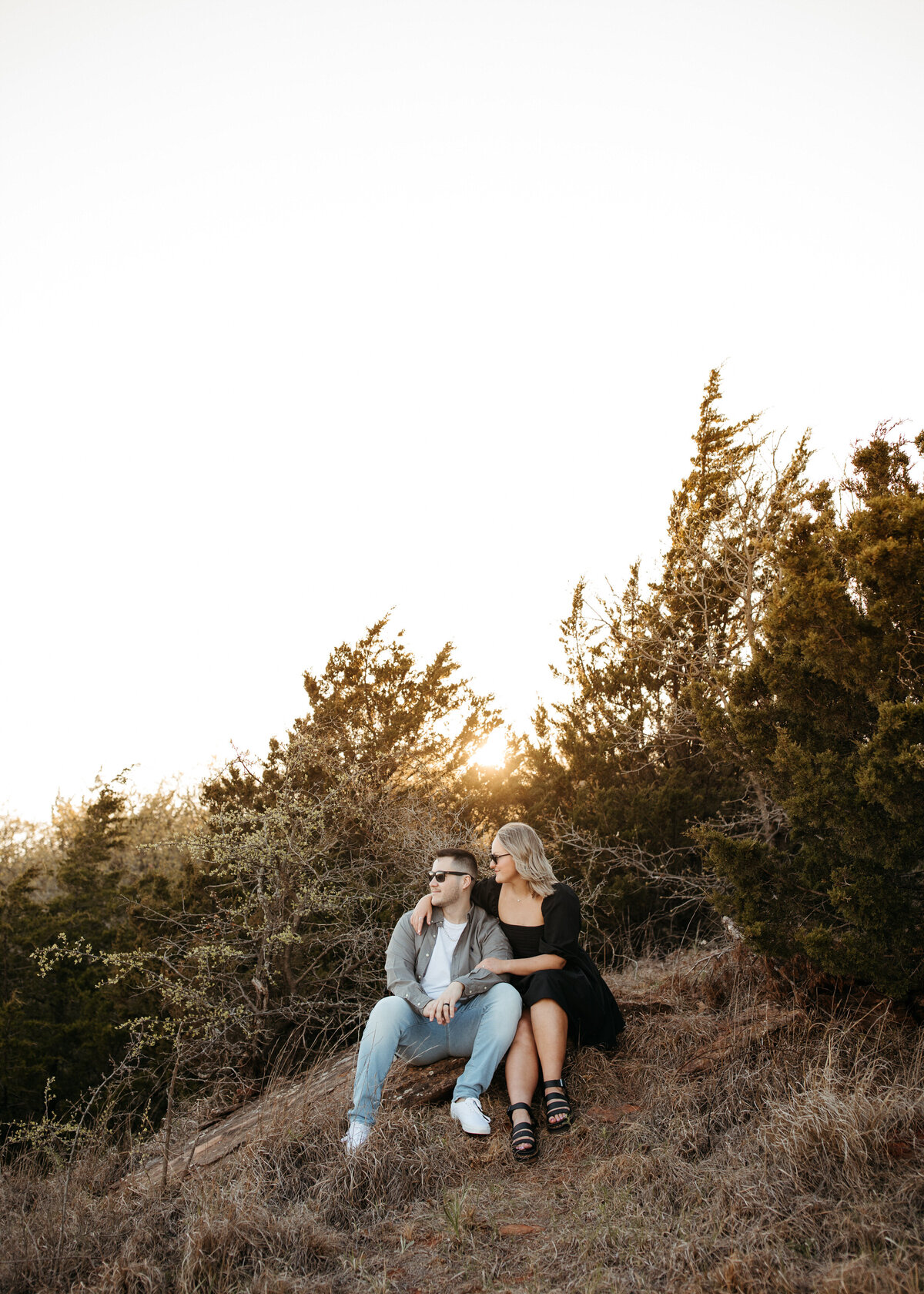 A couple seated on a hillside at dusk, enjoying the peace of the sunset